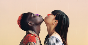 Two women chin touching and looking up with red and purple paint on their noses